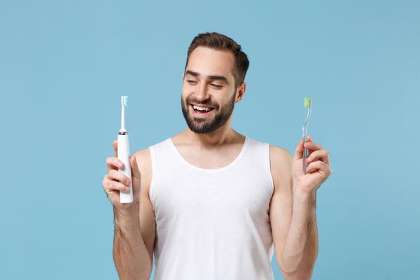 Man weighs up the benefits of using an electric toothbrush